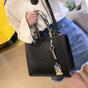 Close-up of black crocodile pattern tote bag featuring snakeskin print handles