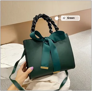 Détail du sac à main vert foncé en cuir mat avec un grand nœud et une poignée tressée