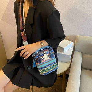 Close-up of woven bucket bag featuring colorful wave patterns and fringe tassels