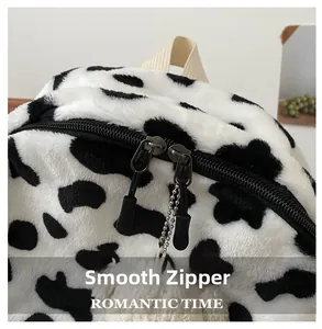Detail of plush cow print backpack with smooth double zippers and soft pompom charm