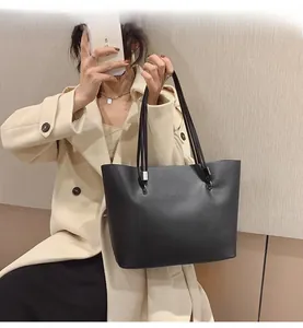 Détail d'un sac cabas noir minimaliste avec lettrage fashion embossé et fines lanières