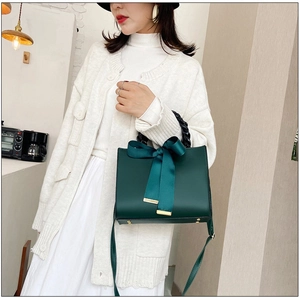 Détail du sac à main en cuir mat vert foncé avec grand nœud en satin et poignée tressée noire