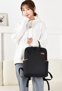 Lifestyle shot of an Asian model wearing a large black oxford fabric travel backpack