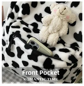 Detail of cow print plush backpack front pocket with phone and cute bear charm