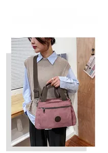 Detail view of pink canvas travel bag with brown straps and adjustable shoulder strap