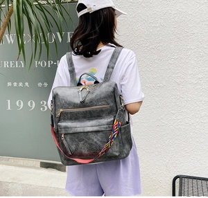 Détail d'un sac à dos gris foncé en similicuir avec bandoulière tissée et zips dorés