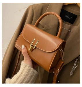 Close-up of caramel leather crossbody bag with gold buckle and adjustable strap