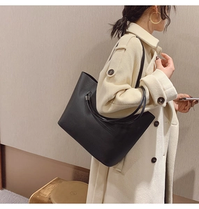 Grand sac cabas noir minimaliste porté sur un mannequin avec un manteau en laine