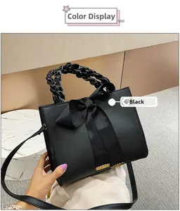 Détail du sac à main noir en similicuir avec poignée tressée et grand nœud décoratif
