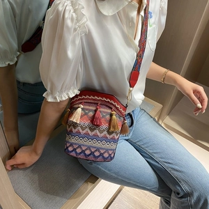 Close-up of bohemian woven bucket bag with colorful tassels and jacquard shoulder strap