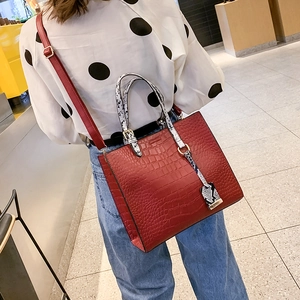 Red crocodile pattern tote bag with snake texture straps shown on a model