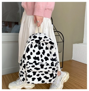 Detailed close-up of fuzzy cow print plush backpack with soft texture and front zipper pocket