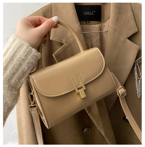 Detail of khaki leather handbag featuring gold H-shaped buckle and cylindrical handle
