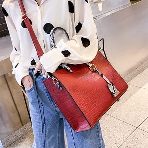 Red crocodile texture shoulder bag styled with printed shirt and blue jeans