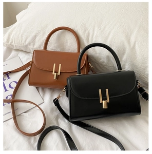 Detail of vintage square crossbody bags in brown and black with gold U-shaped buckles