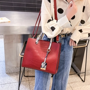 Detail of red crocodile texture handbag with snake pattern handles and gold hardware