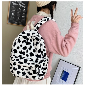 Detail of soft faux fur cow print backpack with spacious front pocket and white handle