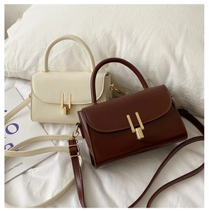 Detail of vintage square handbag with glossy PU leather and golden H-shaped twist lock