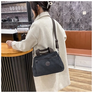 Man carrying a large black canvas travel bag with brown straps in a cafe setting
