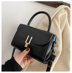 Detail of matte black PU leather handbag featuring a gold buckle and detachable strap