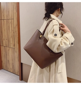 Gros plan d'un grand sac cabas marron avec fines bretelles et boucle dorée élégante