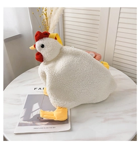 Detail of cute white plush chicken bag with red crest and yellow feet on a white table