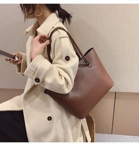 Détail du grand sac cabas en cuir marron avec de longues anses porté sur un manteau beige
