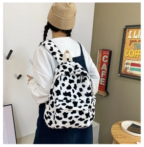 Detail of cow print plush backpack featuring soft faux fur texture and adjustable straps