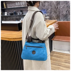 Close-up of bright blue canvas travel bag with leather logo and brown nylon strap details