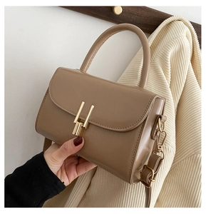 Detail of khaki leather handbag with gold lock and detachable shoulder strap on coat
