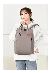 Detail view of stylish grey-purple oxford fabric backpack with brown leather accents