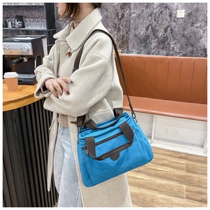 Detail of blue canvas travel bag featuring brown straps and sturdy hardware
