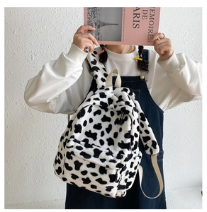 Detail of plush cow print backpack with soft faux fur texture and front zipper pocket