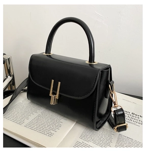 Detail of a black leather handbag with a sleek gold-tone lock on an art magazine