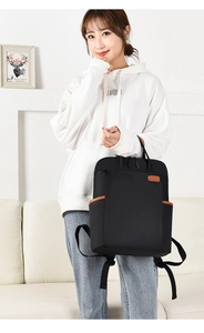 Close-up of black nylon backpack with brown leather details held by a female model