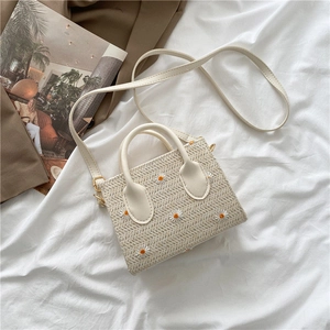 Détail de la broderie de marguerites sur le sac cabas en paille tissée blanc cassé avec anses