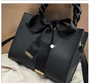 Détail du sac en cuir noir mat avec grand nœud en gros-grain et embouts métalliques dorés
