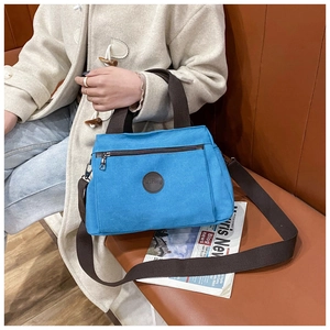 Detail of sky blue canvas travel bag with dark brown straps held by person sitting