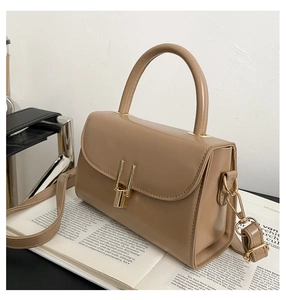 Detail of khaki square crossbody bag with gold metal lock and adjustable strap