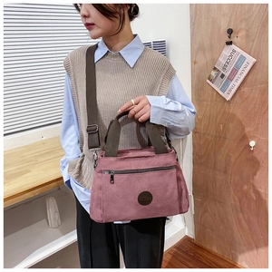 Detail of dusty pink canvas travel bag featuring front zipper and adjustable strap