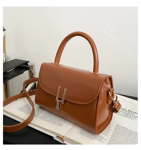 Detailed close-up of brown leather handbag with golden H-clasp on an open magazine