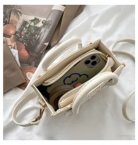 Détail montrant la capacité interne du sac cabas tissé avec téléphone et trousse de maquillage
