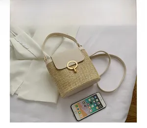 Detail view of woven straw bucket bag with cream leather flap and gold ring lock