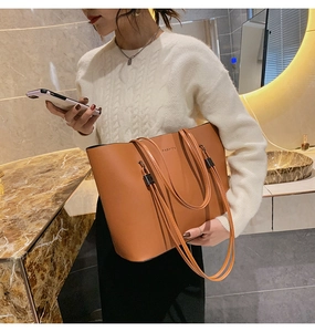 Détail d'un sac cabas en cuir marron caramel avec logo FASHION et garnitures noires