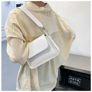 Detailed side view of white PU baguette bag with wide shoulder strap on model