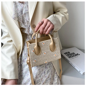 Détail d'un sac cabas en paille tressée avec broderie marguerite et poignée ronde
