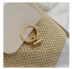 Detail view of the golden metal buckle and woven texture on a straw bucket bag