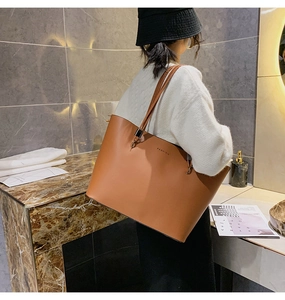 Détail d'un grand sac cabas en cuir marron avec l'inscription FASHION porté par un mannequin