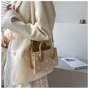 Mannequin portant un petit sac cabas en paille avec broderie marguerite et bandoulière