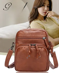 Detail of caramel multi-pocket crossbody bag showing tiered zippers and leather texture